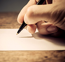 Hand holding pen writing a letter