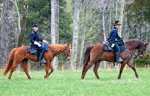 Historical re-enactors ride horses at the stamp dedication ceremony.