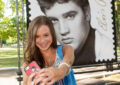 Isabella Scott, president of the Youngest Elvis Presley Fan Club, snaps a selfie in front of the stamp display.