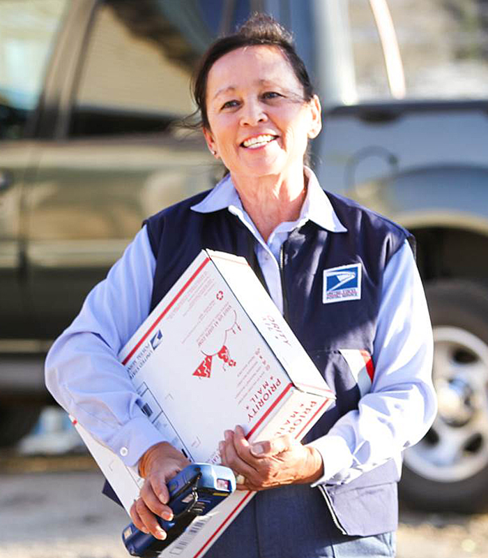 An employee with a Priority Mail package and a Mobile Delivery Device.