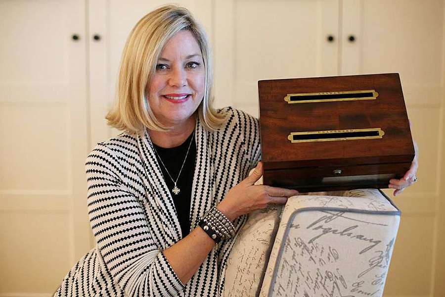 Dallie Clark — a humanities professor at Collin College in Plano, TX — holds an antique letter box.