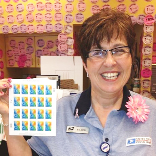 Punta Gorda, FL, Retail Associate Eileen Dimase holds a sheet of Breast Cancer Research stamps.