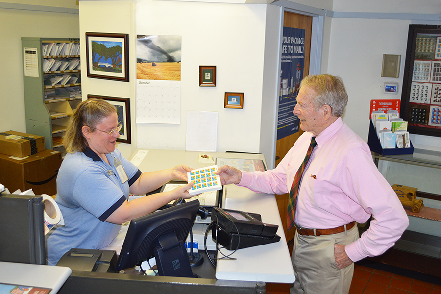 James Island, SC, Sales Associate Dian Dean sells breast cancer stamps to Eugene Platt in October. Platt has purchased $14,000 worth of the stamps since 2003, when his wife died of the disease.