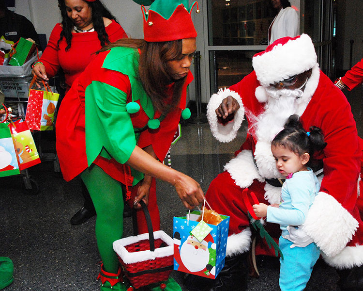 Chicago Acting Postmaster Tangela Bush and Santa Claus (Mechanic Eddie Spearman) pass out gift bags at a recent Operation Santa event.