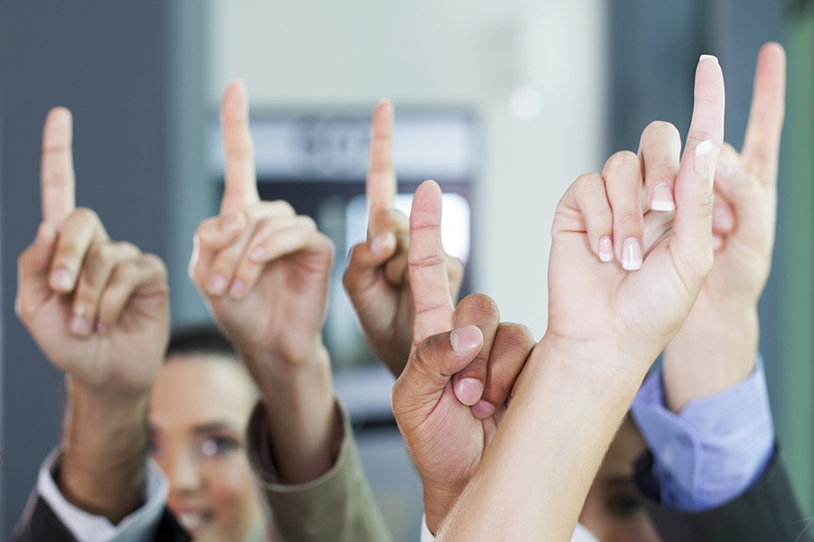 A group of people holding up their fingers to signify that they're number 1.