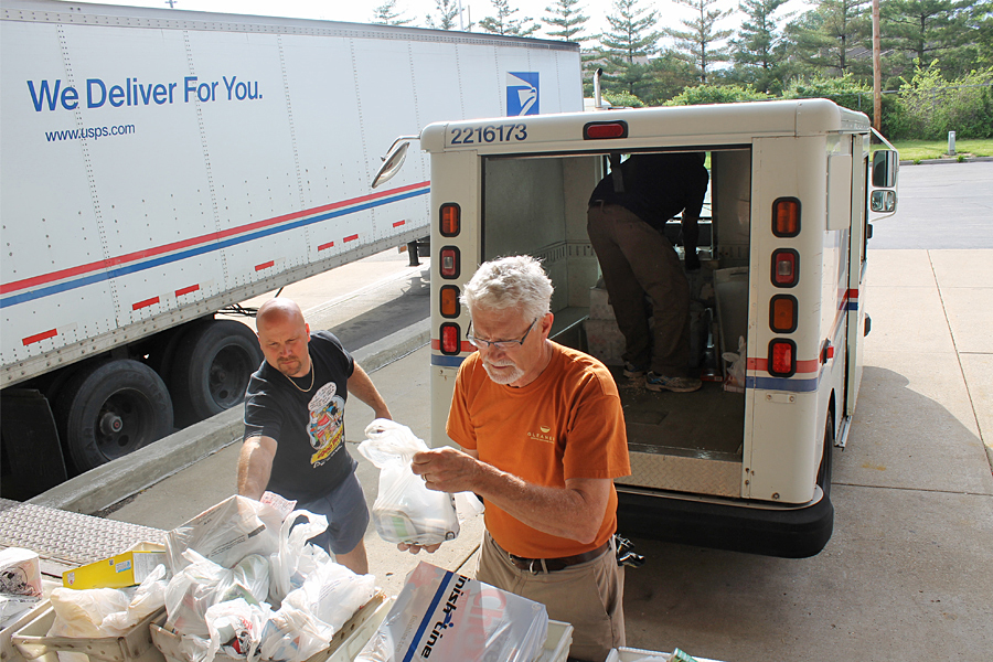 Indianapolis Letter Carrier Paul Connor and volunteer Norm Metzler stack food donations during last year’s Stamp Out Hunger drive.