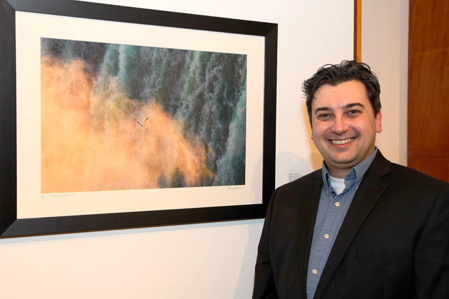 Kevin Ebi stands near one of his photographs of the Niagara Falls National Heritage Area at an exhibit in Los Angeles.