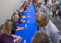 Participants autograph programs for stamp collectors at the show, which is being held in New York City.