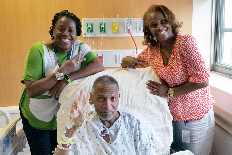 USPS Headquarters Maintenance Supervisor Gwendolyn Harvey and Purchasing and Supply Management Training Coordinator Alice Parks visit Maintenance Operations Manager Derrick Coleman in the hospital.