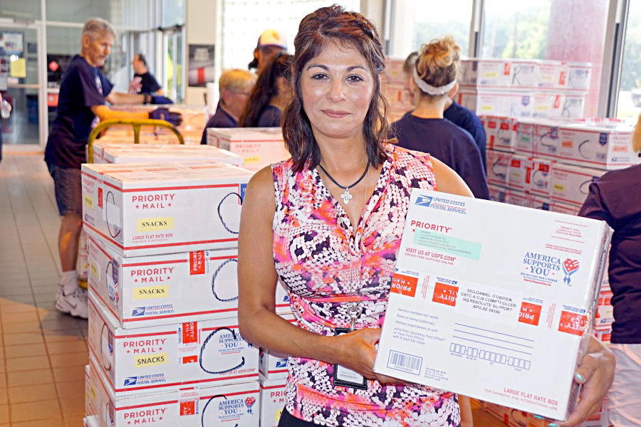 Postmaster Natalie Barrios stands near care packages recently shipped through the Clute, TX, Post Office.