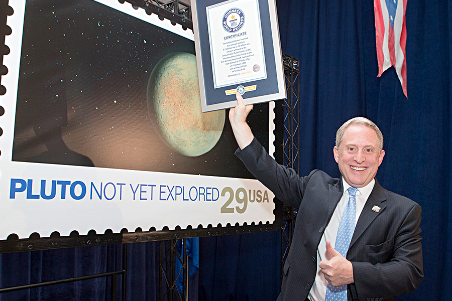 New Horizons Principal Investigator Alan Stern holds one of the Guinness world record certificates presented to the Postal Service and NASA July 19.