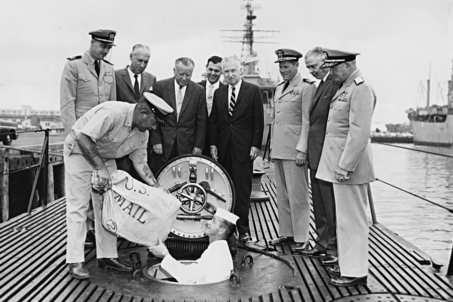 Postmaster General Arthur Summerfield, fourth from left, postal officials and U.S. Navy personnel watch the loading of missile mail into the Navy submarine USS Barbero.