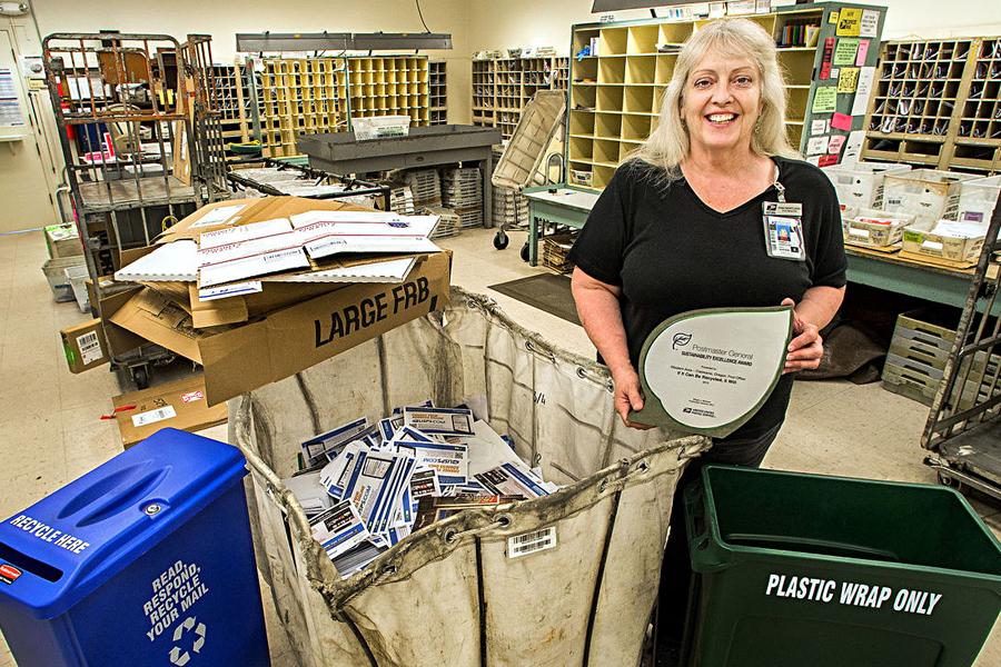 Clatskanie, OR, Postmaster Pam Wantland displays her Postmaster General Sustainability Award, which is made of recyclable materials. Image: The Daily News