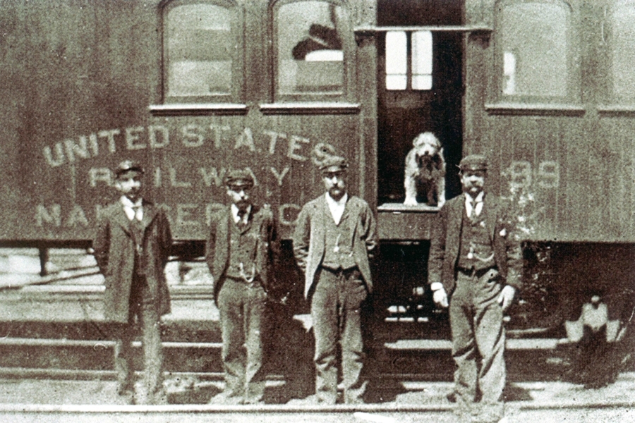 Owney stands inside a train near his railway mail clerk friends. Image: National Postal Museum