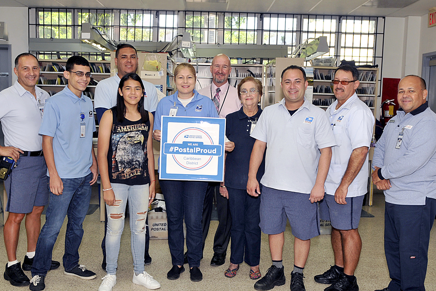 Adrianna Diaz, fourth from left, expresses her postal pride alongside the Utauado, PR, Post Office team, including Postmaster Carlos Roman, sixth from left.
