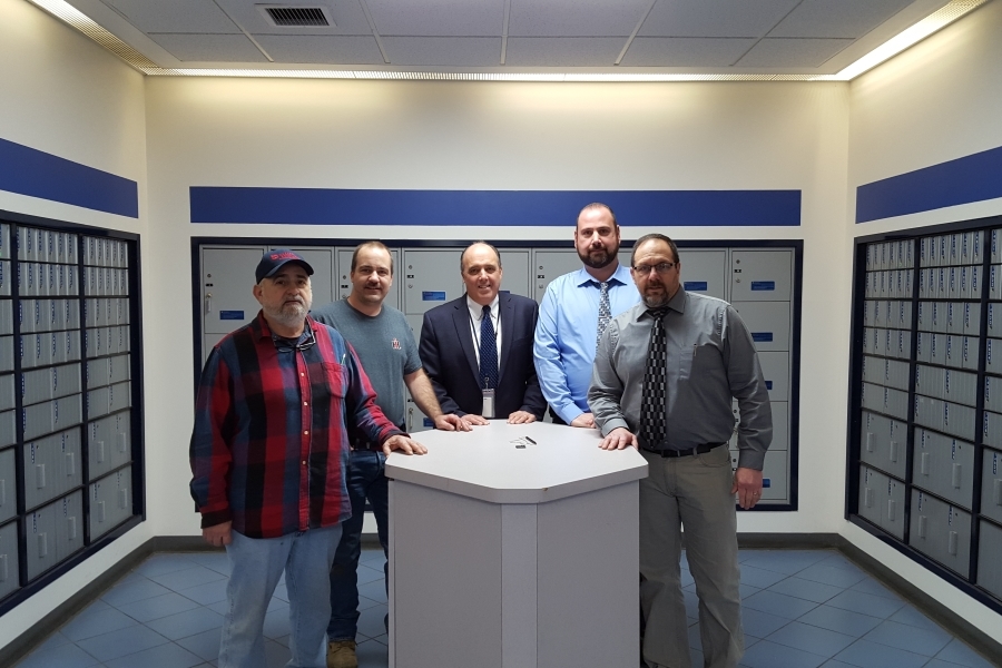 Gathering inside the Albany, NY, Post Office lobby are, from left, Rick Nicklaw, maintenance mechanic; Jody Adams, building equipment mechanic; Postmaster Joseph Finan; Christopher Campion, maintenance engineering support manager; and Robert Florio, acting maintenance supervisor.