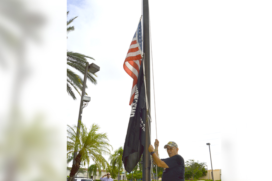 Miami Custodian Lazaro Julve raises the U.S. and POW-MIA flags in front of the Miami General Mail Facility recently.