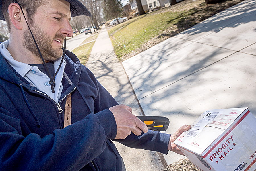 Madison, WI, Letter Carrier Jim Haasch scans a package before delivering it earlier this year. Households received 3.8 billion packages during fiscal 2015, new research shows.