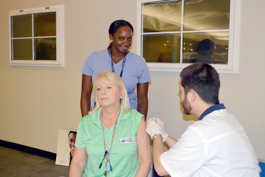 At a recent clinic at the Columbia, SC, Processing and Distribution Center, USPS Occupational Health Nurse Jessica Wilson watches a Rite Aid representative give a flu shot to Bulk Mail Clerk Patricia Mowery.