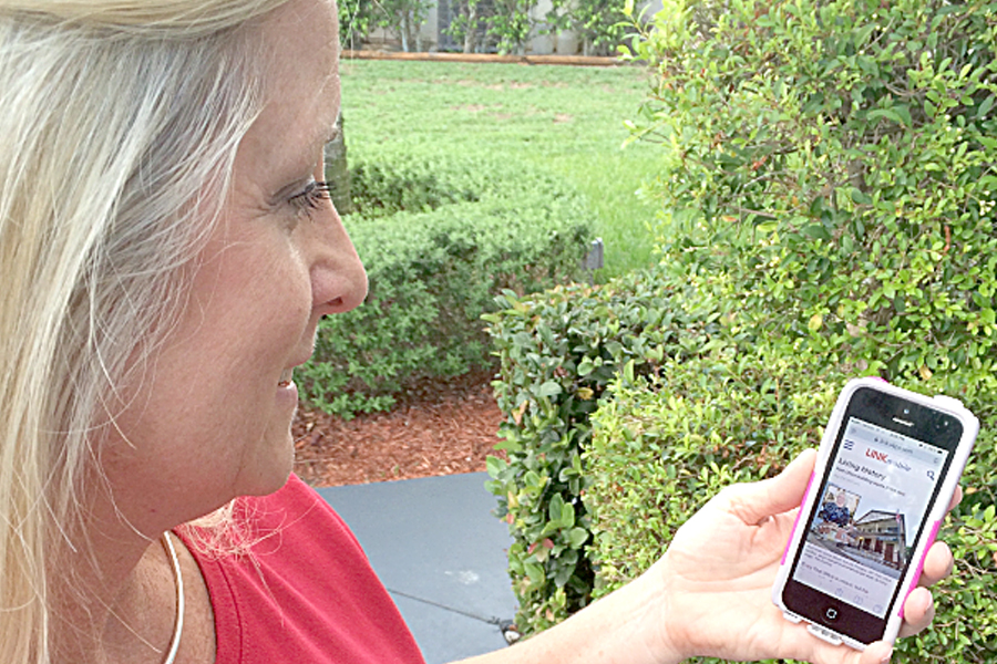 West Palm Beach, FL, Address Management Systems Technician Karin Nolf reads Link mobile on her smartphone.