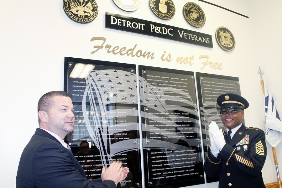 Plant Manager Ron Morris and Maintenance Supervisor William Russell unveil a veterans’ wall at the Detroit Processing and Distribution Center (P&DC) last week.