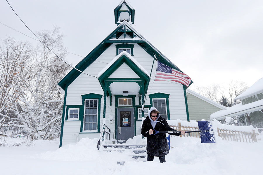 Pamela Bentley, a USPS retail associate and distribution clerk, shovels snow in front of the Grafton, NY, Post Office last week. Image: AP Photo by Mike Groll