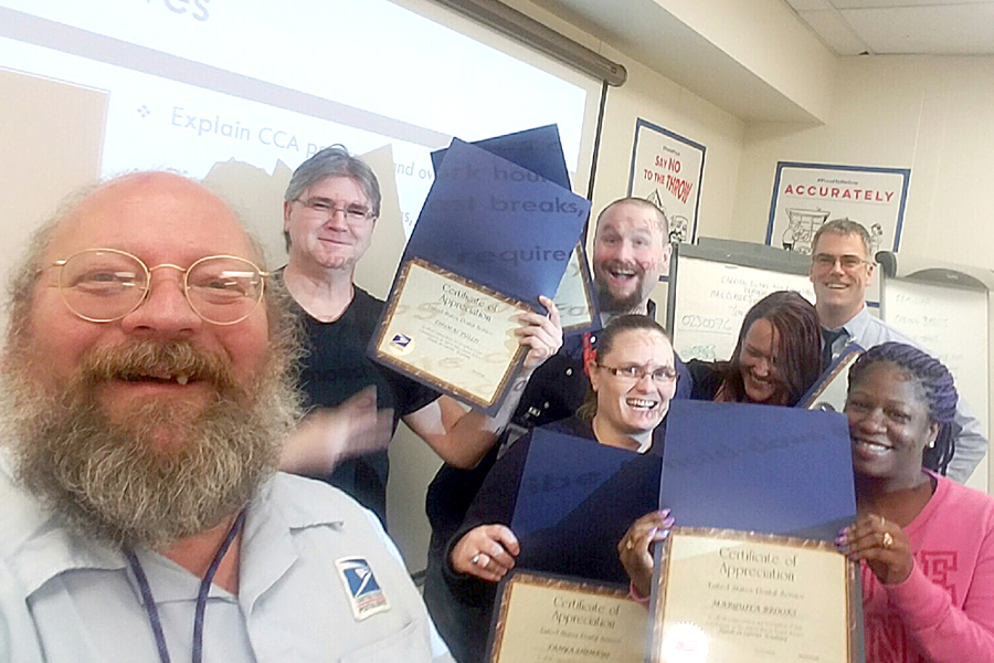 Letter carriers and instructors Michael Erdelyi, front, and Travis Holt, back, gather with graduates of the first City Carrier Assistant Academy in Anchorage, AK.