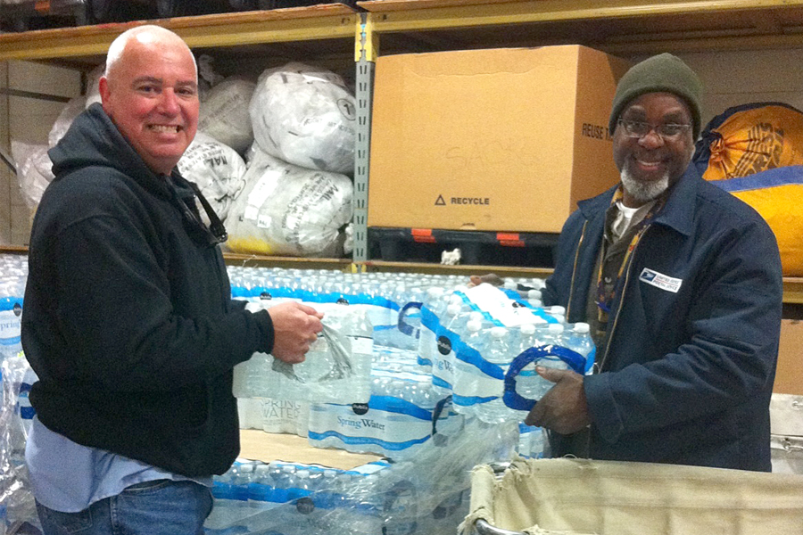 Michael Soliz, a maintenance custodian, and Alfred Littles, a mail handler, load cases of water for distribution to employees at the Corpus Christi, TX, Processing and Distribution Center this month.