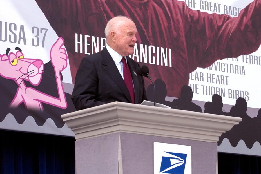 John Glenn helps the Postal Service unveil the Henry Mancini stamp in 2004.