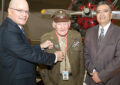 Williams presents a pin to Wilbur Richardson, a World War II veteran and docent at the Planes of Fame Air Museum, with help from Santa Ana District Manager Eduardo Ruiz.
