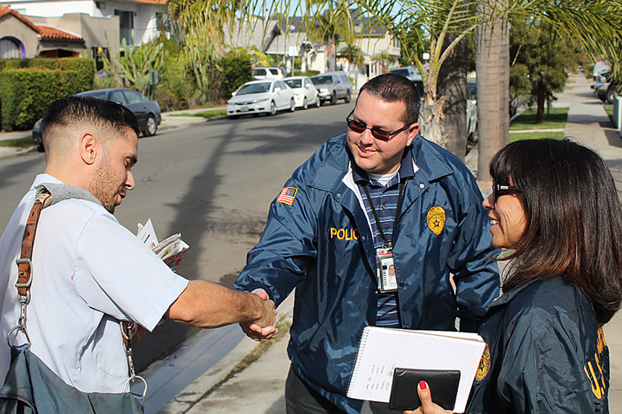 San Diego, CA, Letter Carrier Julio Mendroza is greeted recently by postal inspectors Patricia Mendoza and Cory Blott.