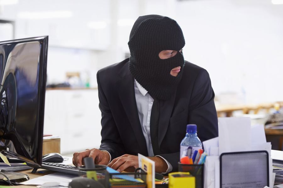 Man in mask types at computer