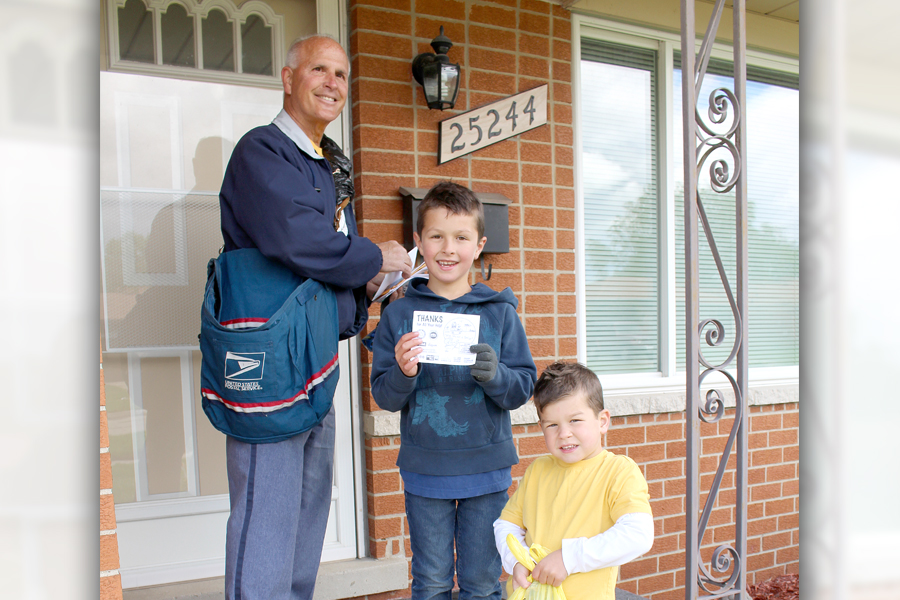 Letter carrier poses with two young boy kids