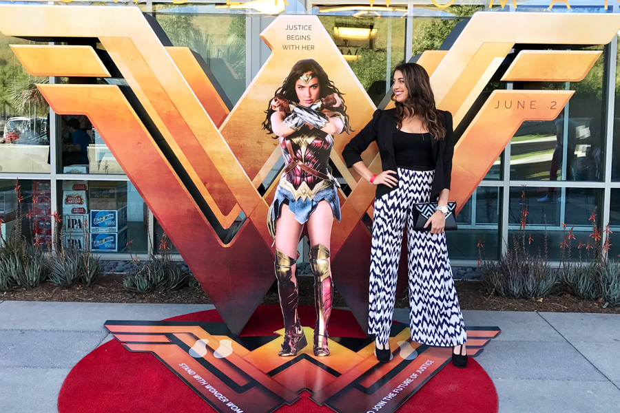 Woman stands next to Wonder Woman poster