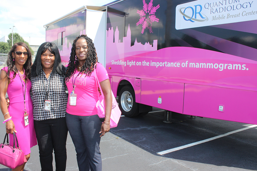 Three women stand next to pink bus