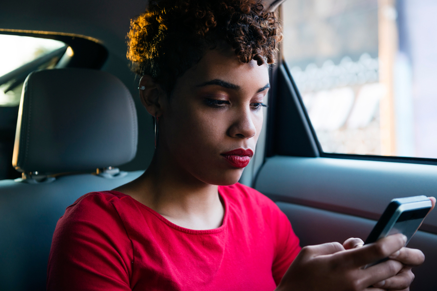 Red-shirted woman looks at phone in car