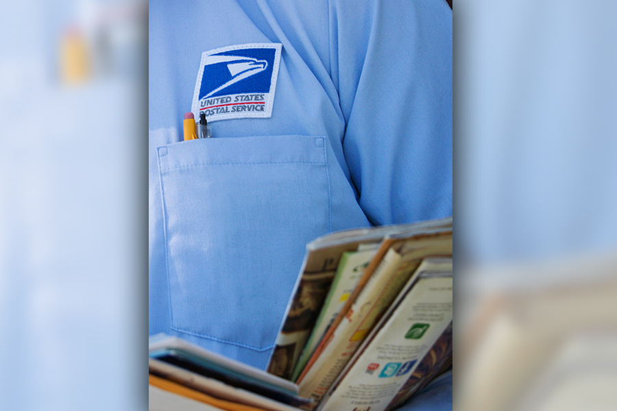 Letter carrier's arms carrying mail