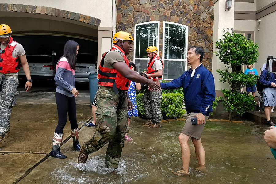 National Guard soldier shakes hands with man outside flooded home