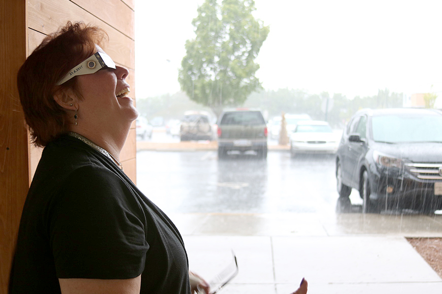 Employee wears eclipse-viewing glasses in rainstorm
