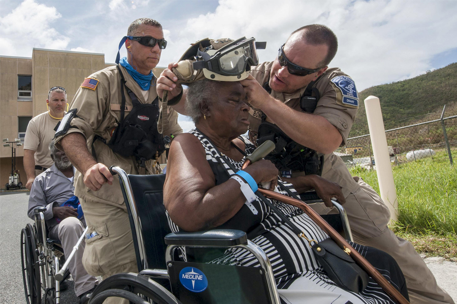 Military rescue workers help elderly woman