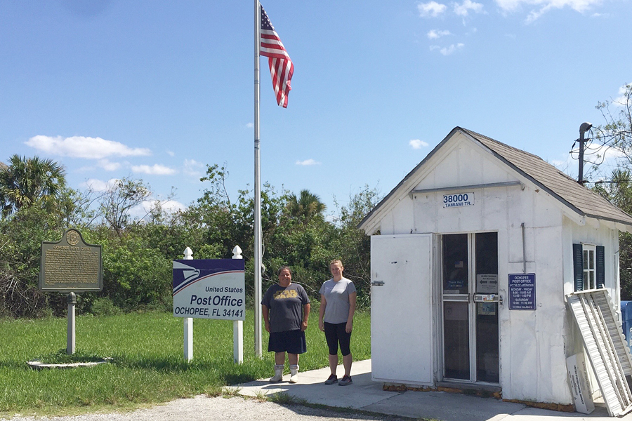 Two women stand near tiny Post Office building