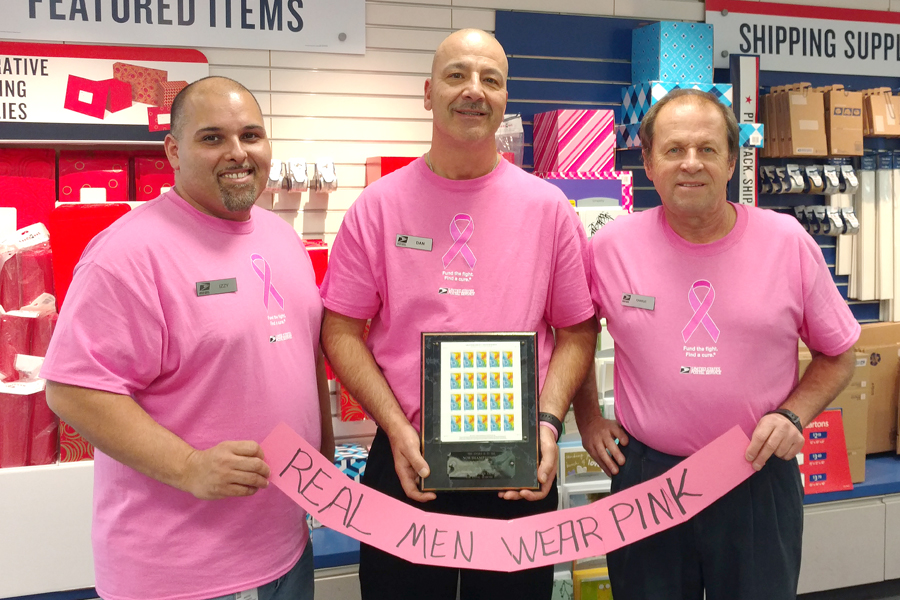Three men wear pink with banner