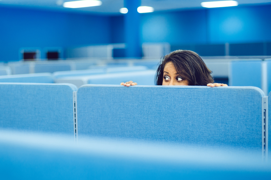 Woman peeks over cubicle