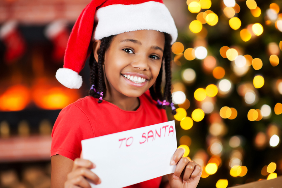 Child wearing Santa hat and holding letter