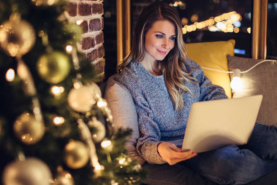 Woman on computer by Christmas tree