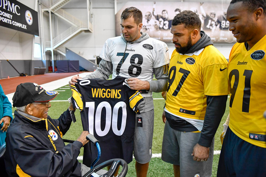 Football players present jersey to older man in wheelchair