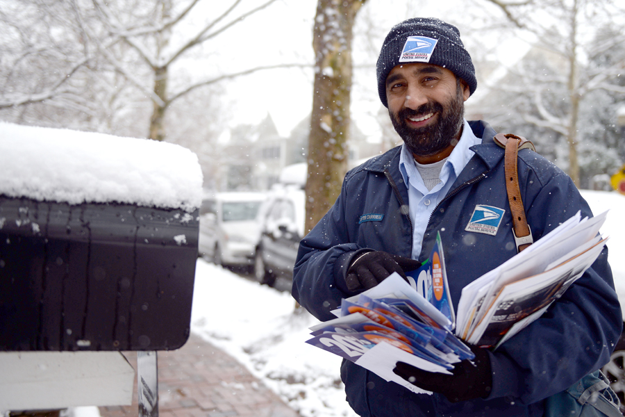 USPS letter carrier delivers mail on snowy street