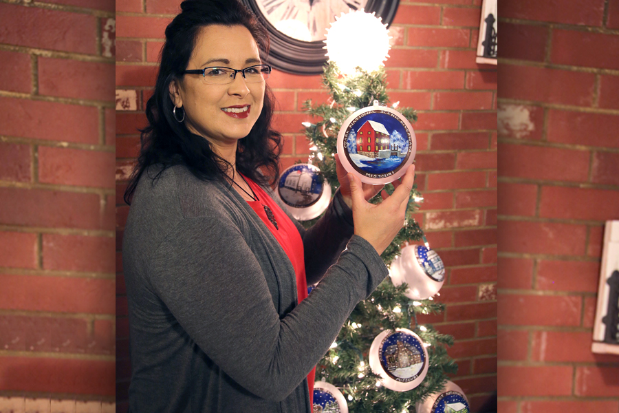 Woman holds ornament near Christmas tree