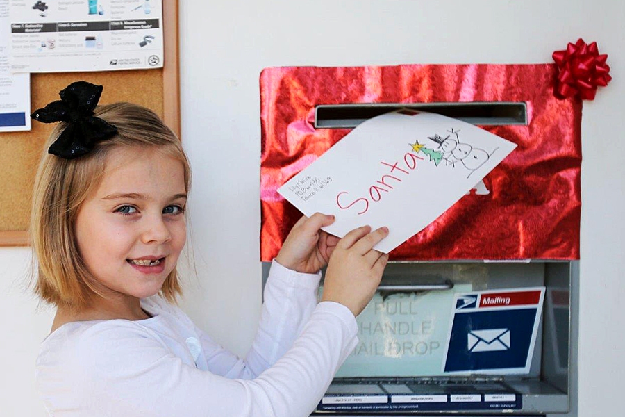 Little girl holds letter to mailbox