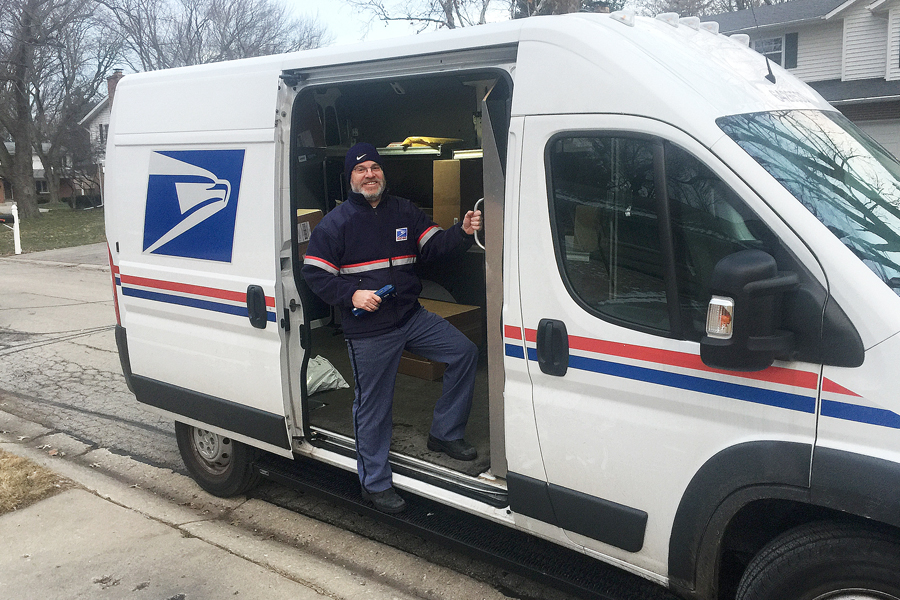 USPS carrier stands inside delivery van